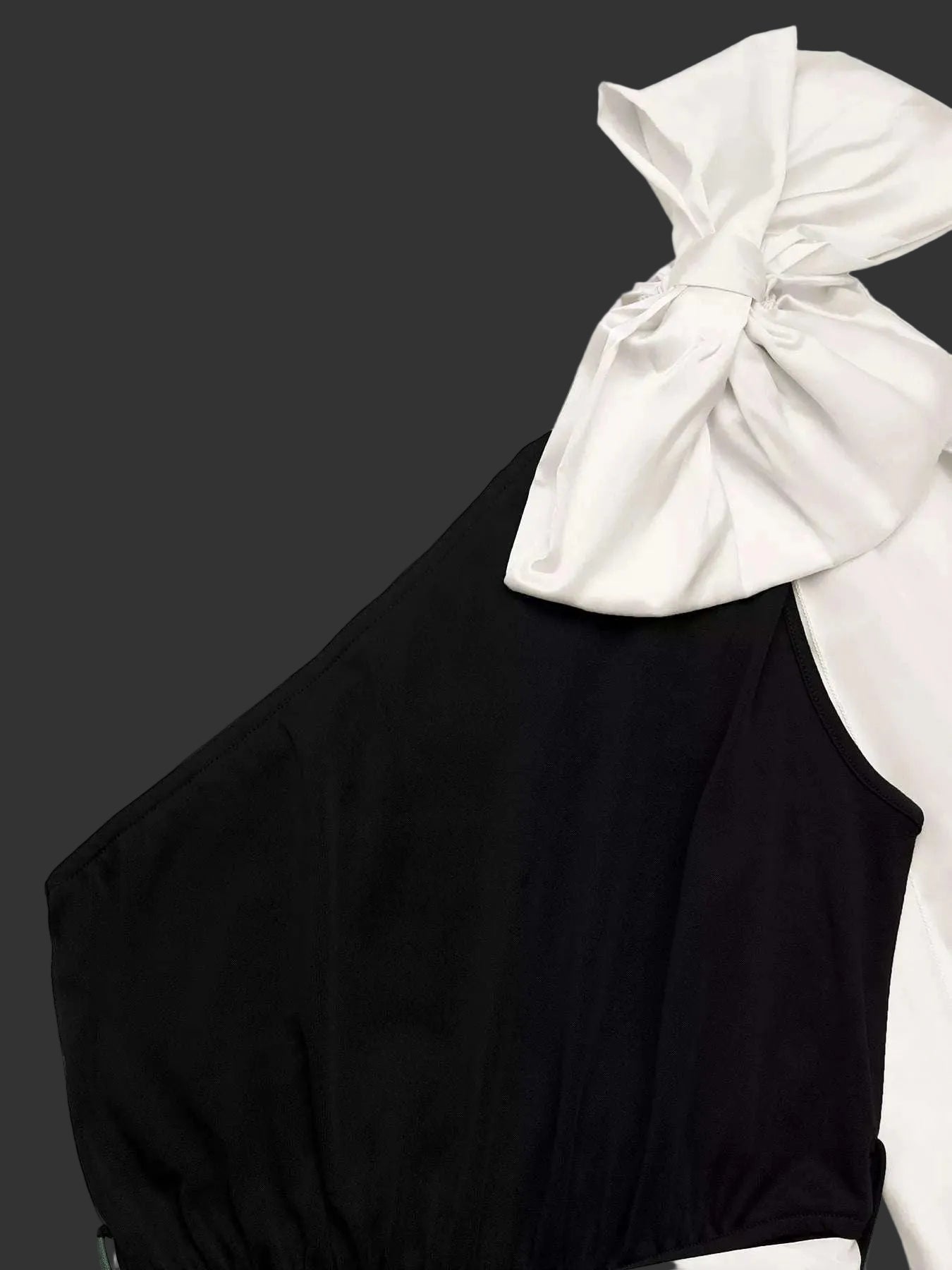 Black sleeveless top with a white bow on a white background