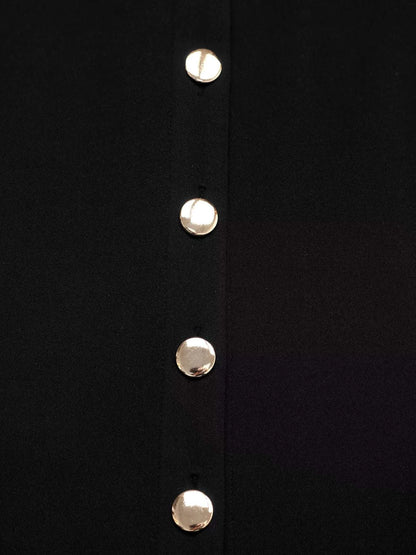 Close-up of a black garment with gold buttons on a white background